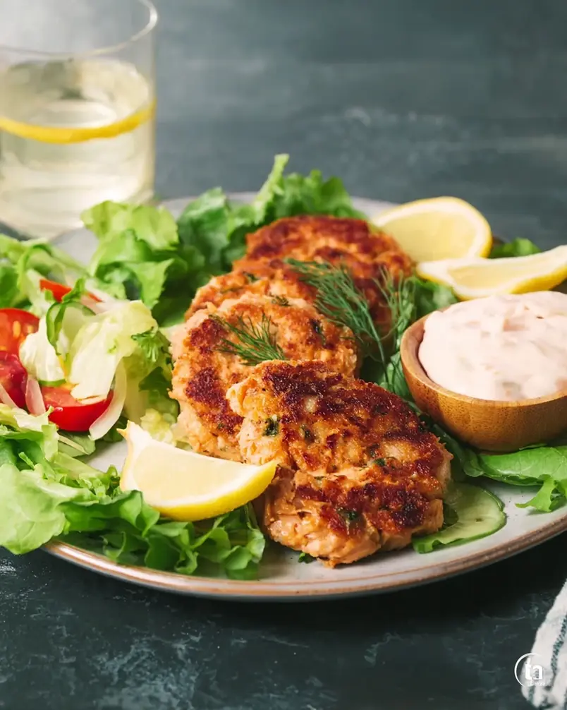 Grandma's Famous Salmon Cakes 2 A close-up shot of flaked salmon and breadcrumbs being mixed in a bowl, with hands gently combining the ingredients.